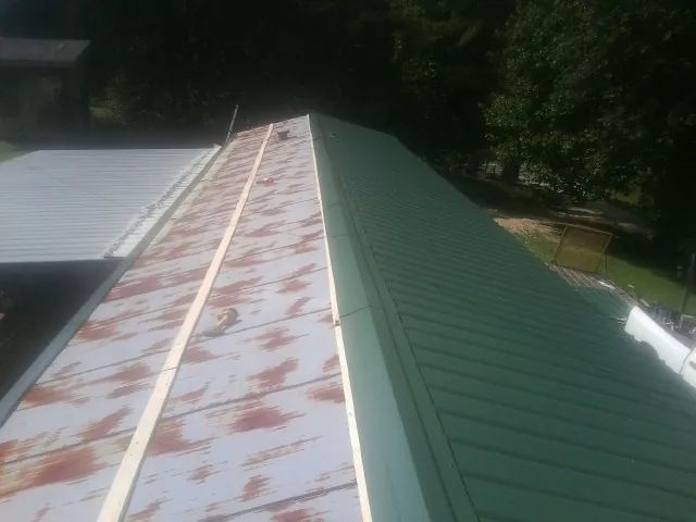 Old rusted panels beside newly installed green metal roofing — Wind Damage Roof Repair by Roofing Brothers in Wanaque