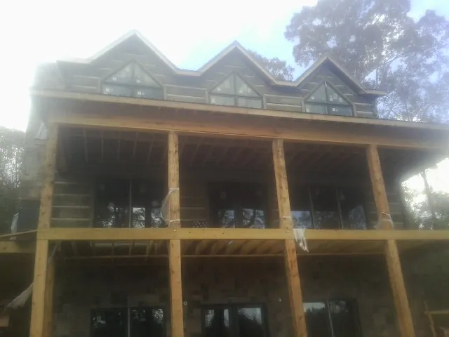 Dormers and porch framing on a large log home under construction — Roof Coating work by our crew in Wanaque