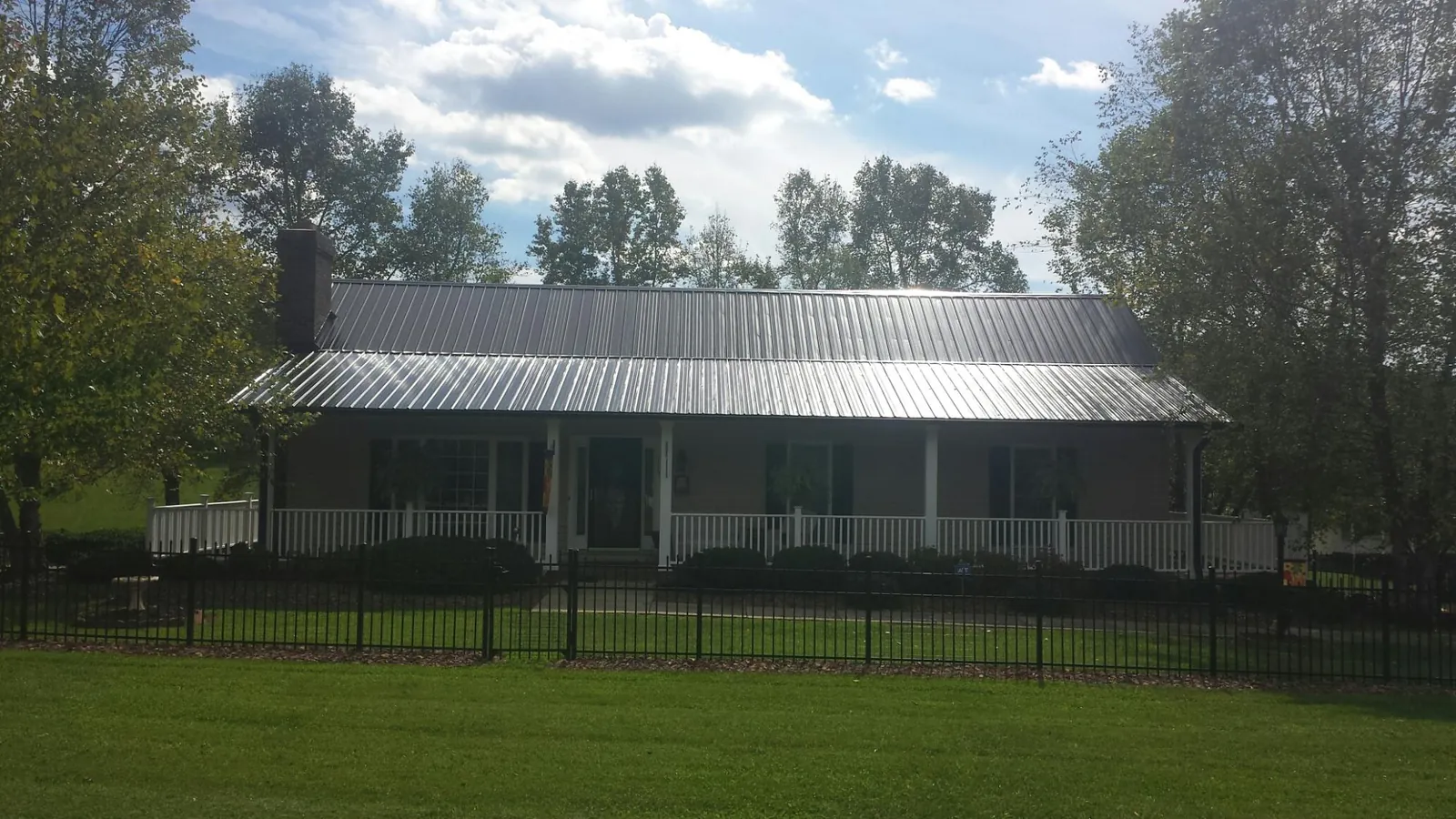 Gray metal roof on a brick ranch with a full width front porch — Gutter Guard Installation work by our crew in Wanaque