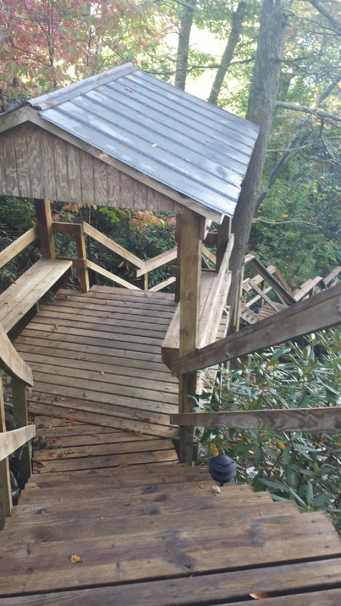Metal roofed shelter over wooden steps on a wooded walkway — Skylight Repair & Installation work by our crew in Wanaque