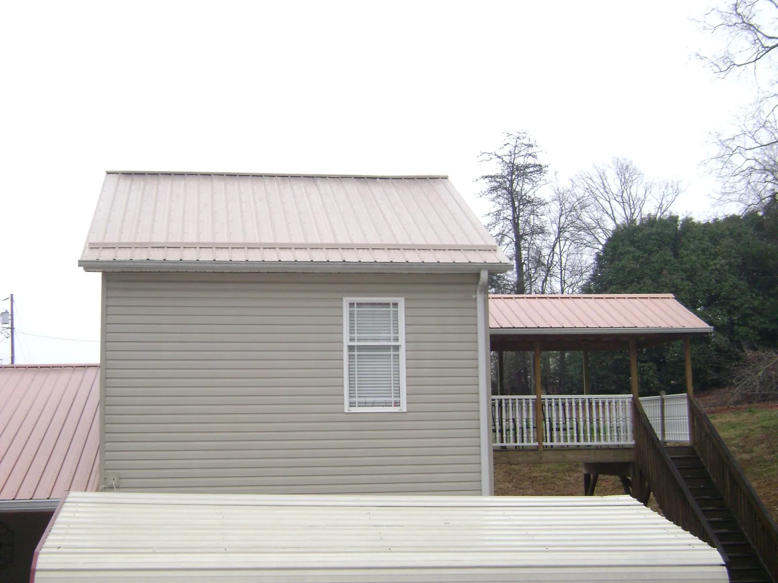 Tan metal roofs on a two story addition and attached porch, from a Roof Replacement job in Wanaque