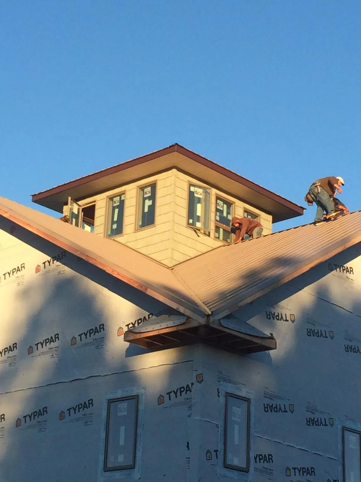 Roofers working around a rooftop cupola on a new metal roof at sunset — Roof Waterproofing in Wanaque by Roofing Brothers